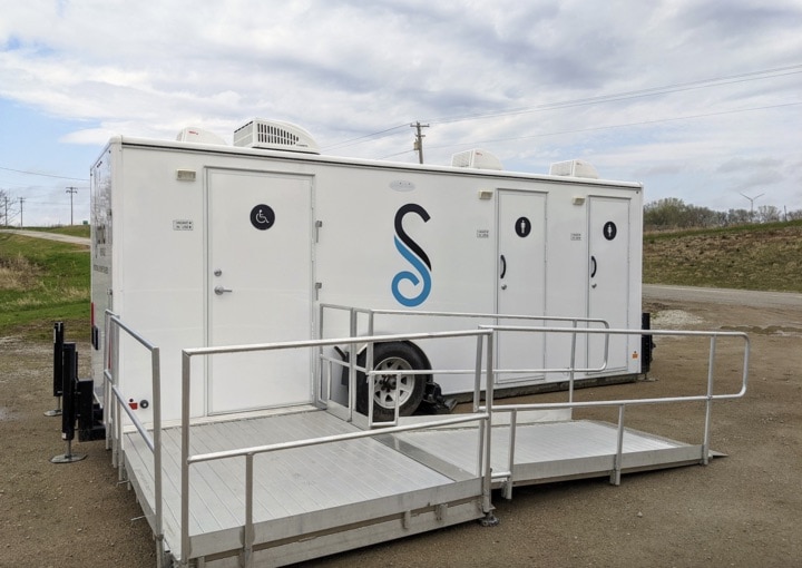 Mobile restroom trailer with ramp outdoors.