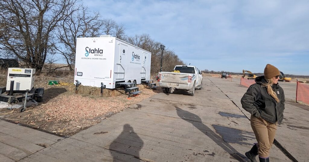 Construction site with portable restroom trailers and vehicles.