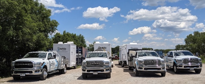 Fleet of RAM trucks with white Stahla trailers parked.