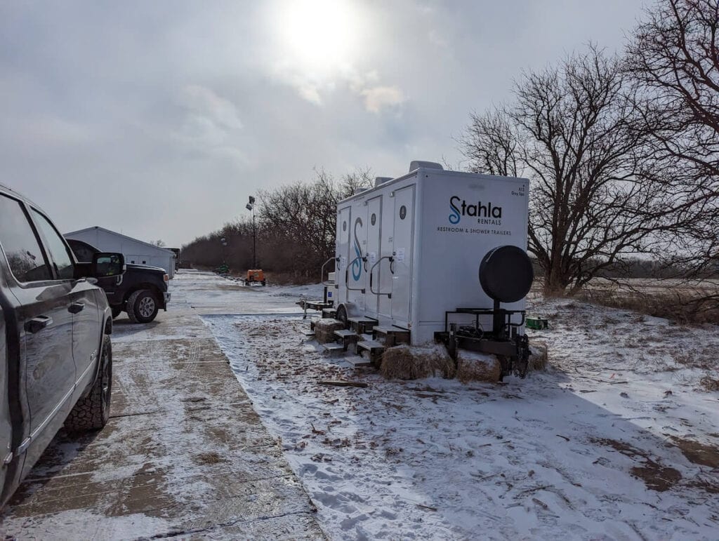 Mobile restroom trailer parked in snowy lot.