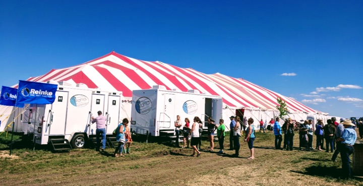 Outdoor event with people and striped tent.