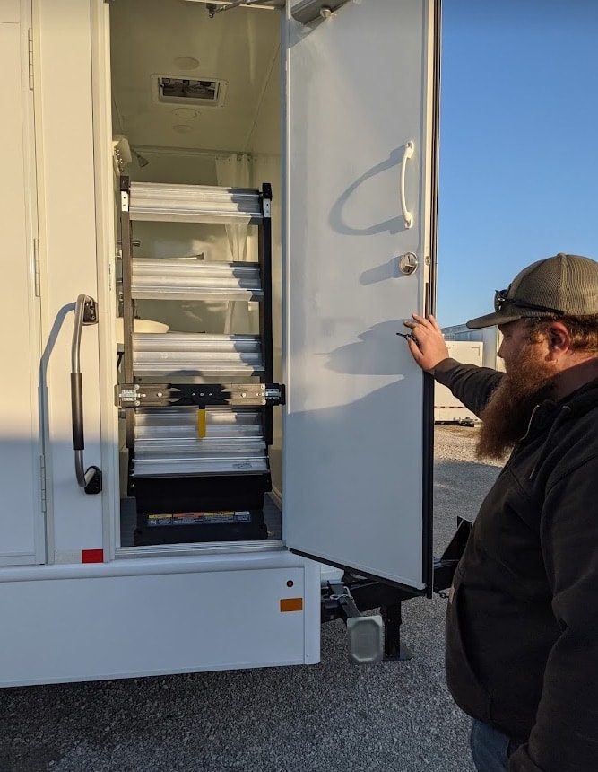 Man inspecting retractable RV steps at dusk.