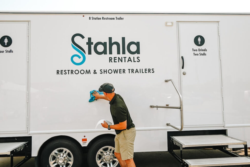 Man cleaning a portable restroom trailer.