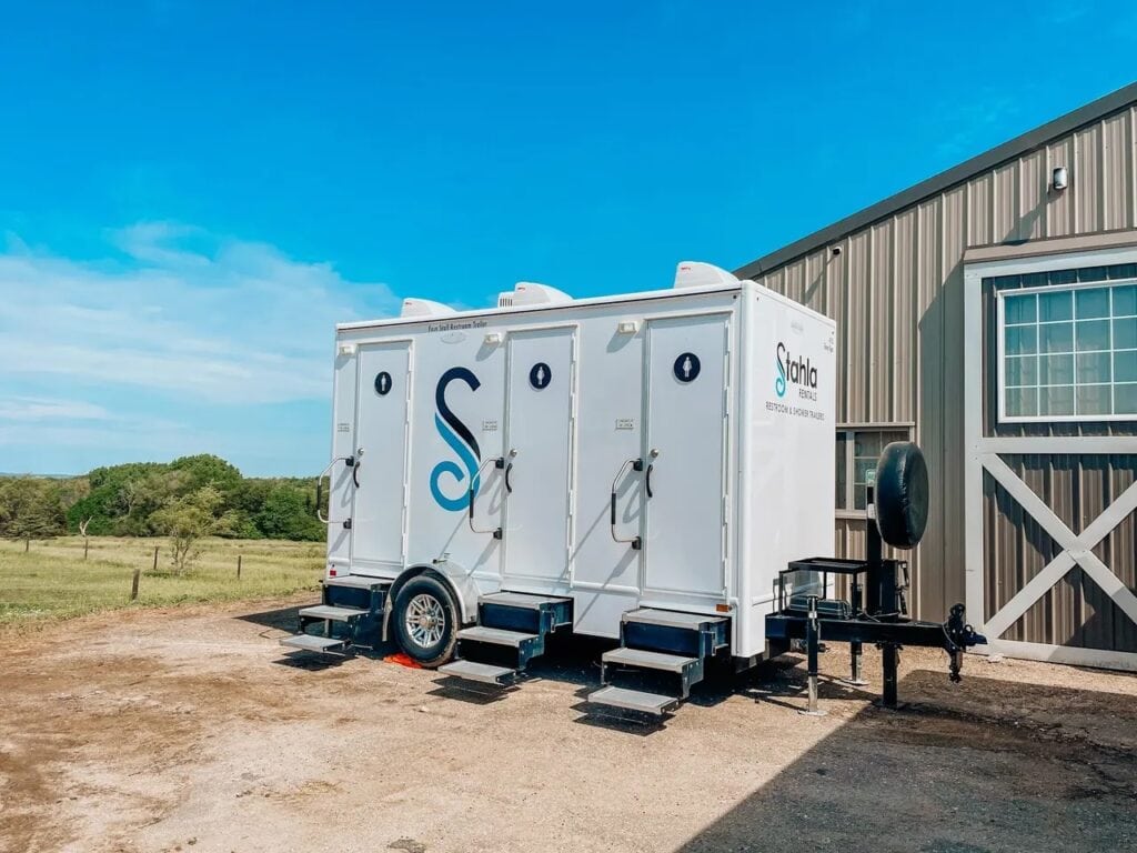 Portable restroom trailers by building.
