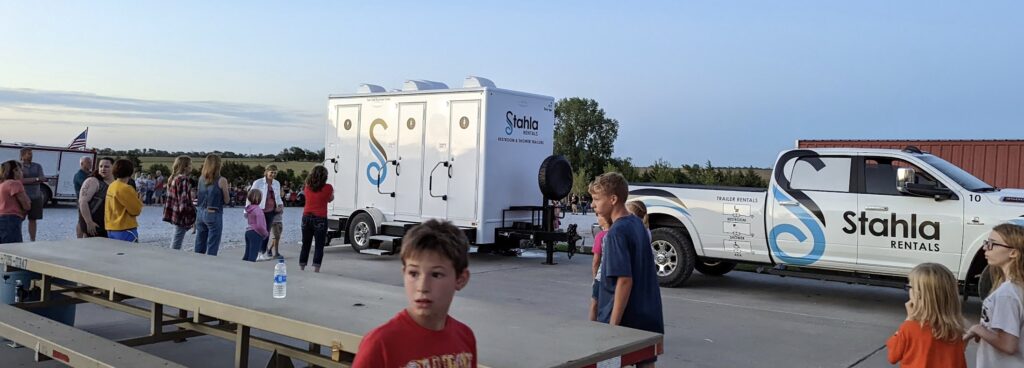 Outdoor event with portable restrooms and pickup truck.
