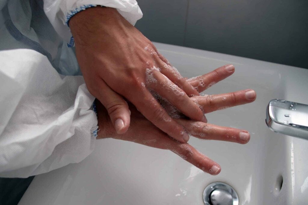A person washing their hands with soap over a sink, raising questions about whether men or women perform this task better.