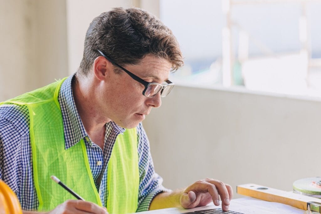Construction worker reviewing blueprints on site