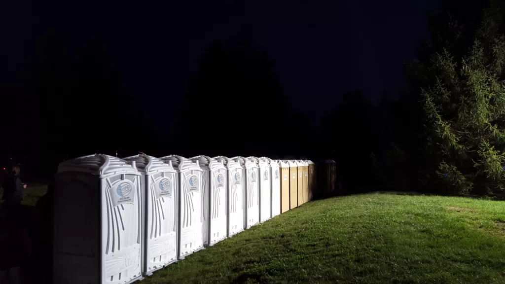 Row of portable toilets at night event.