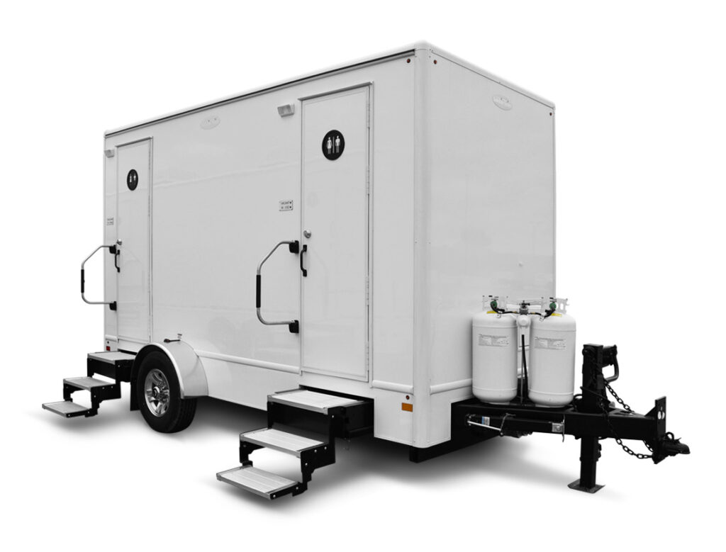 White mobile restroom trailer with stairs and propane tanks.