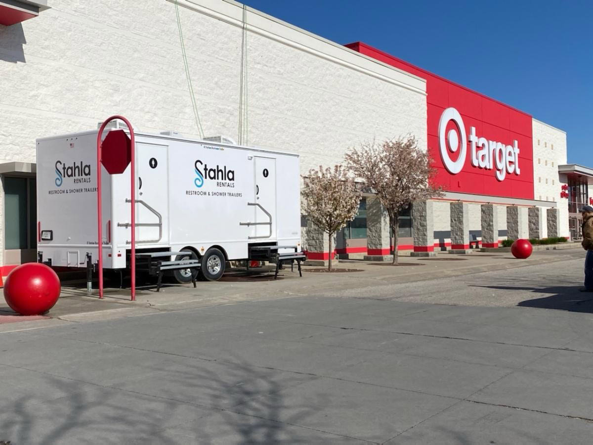 a target store with a white 8 stall restroom trailer rental and shower trailer parked outside near the entrance. large red bollards are positioned in front of the store.