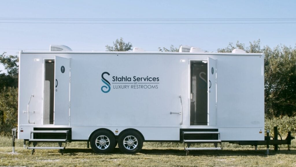 Mobile luxury shower restroom trailer parked on grassy terrain.