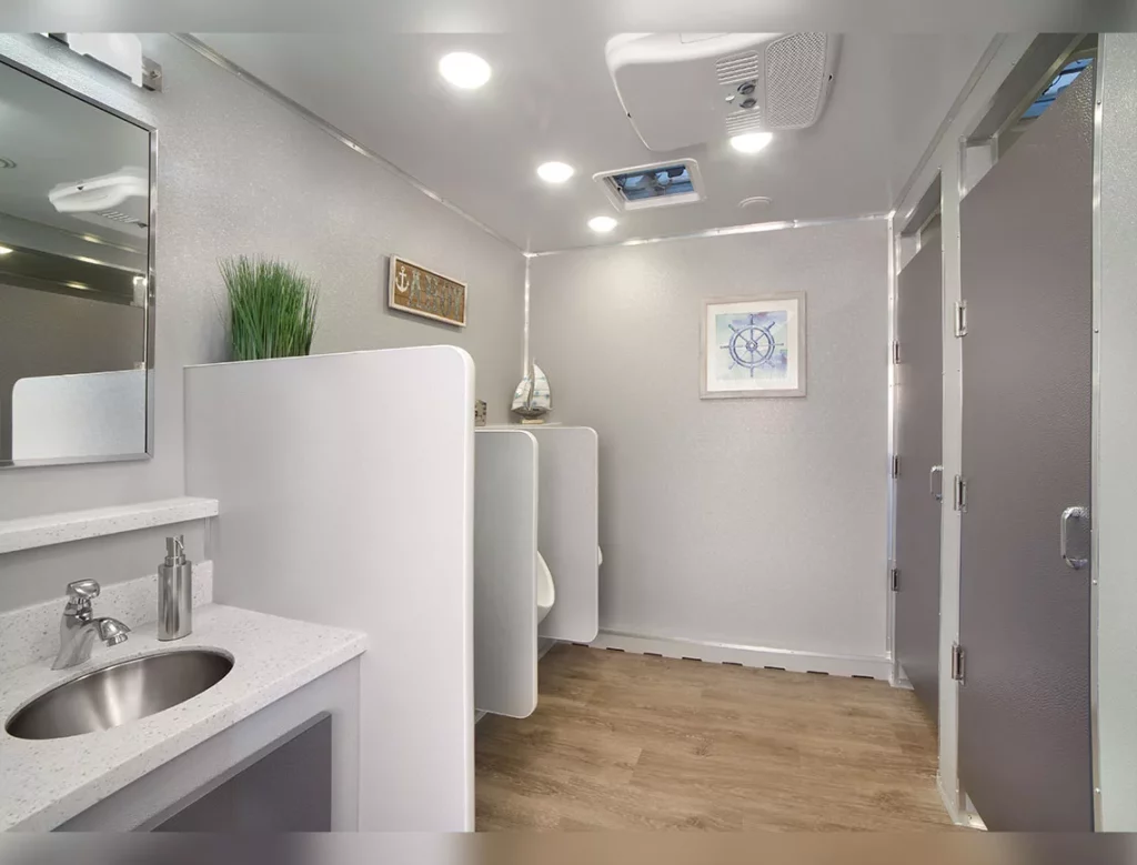 interior of a 10 stall restroom trailer with sinks, and decorative elements like plants and framed pictures.