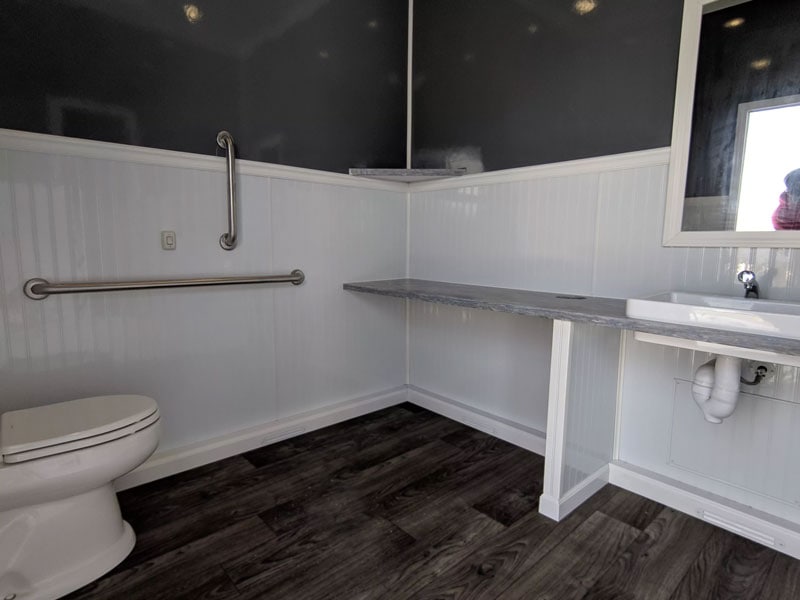Accessible bathroom with grab bars and dark wood floor.