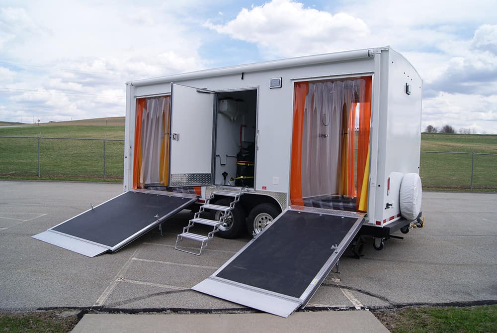 Accessible mobile shower unit with ramps and curtains.