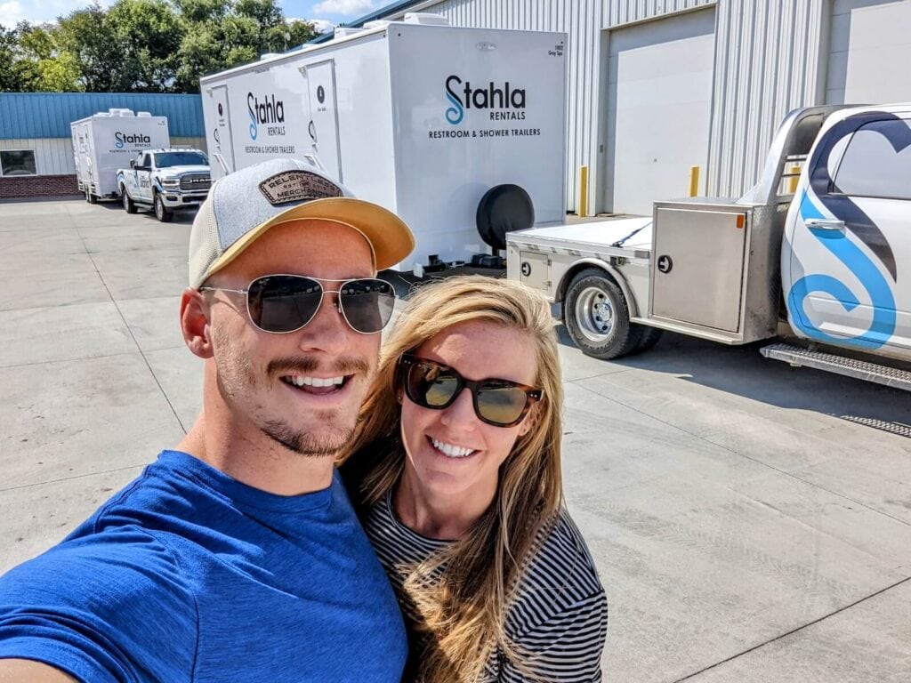 Couple selfie with Stahla Rentals trailers in background.