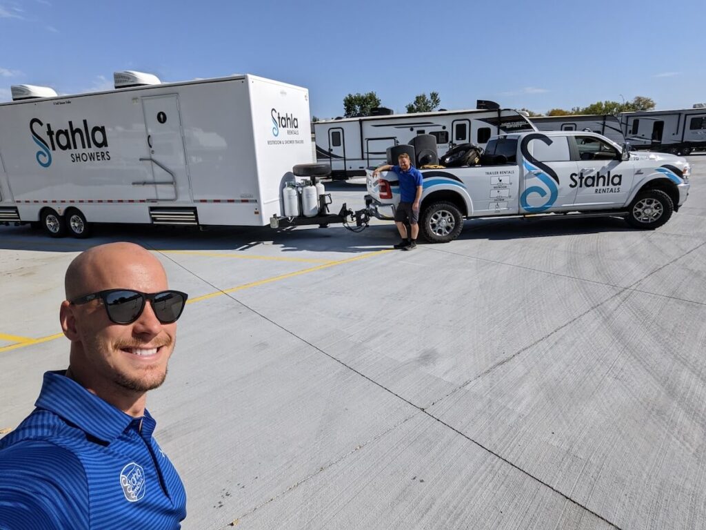 Man taking selfie with mobile showers trailer and truck.
