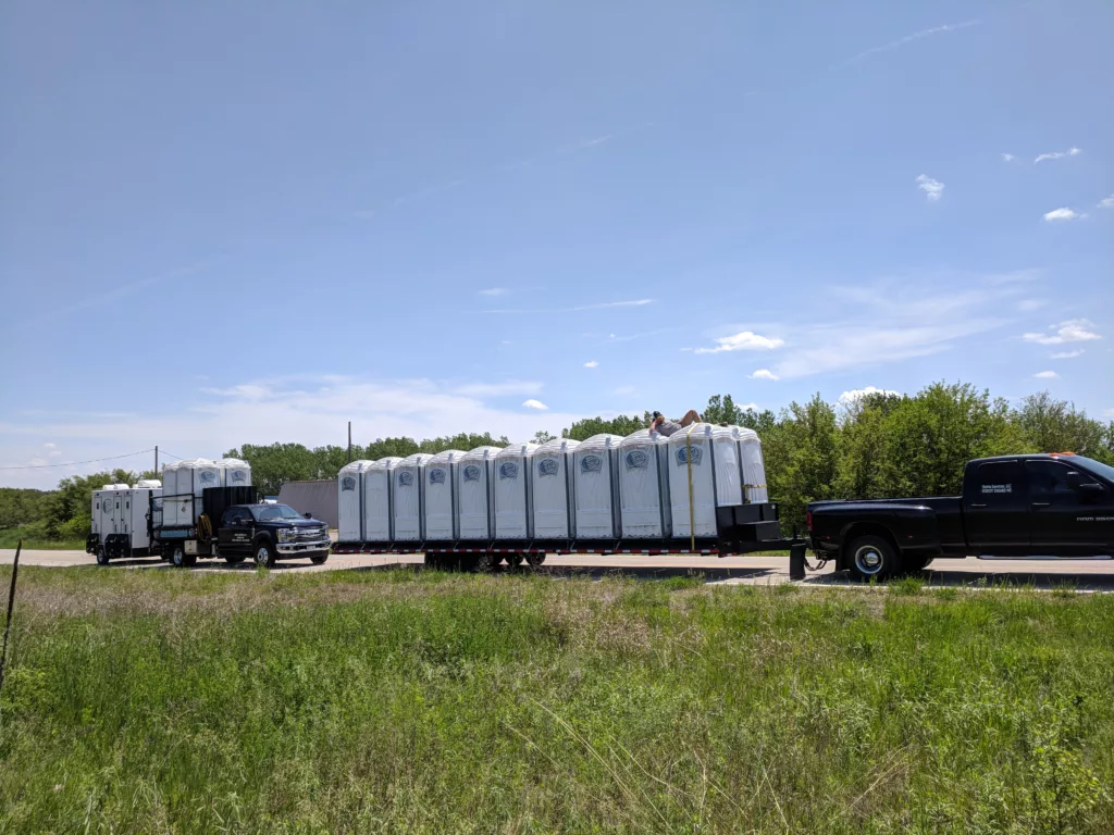 Portable toilets transported on trailer by trucks.