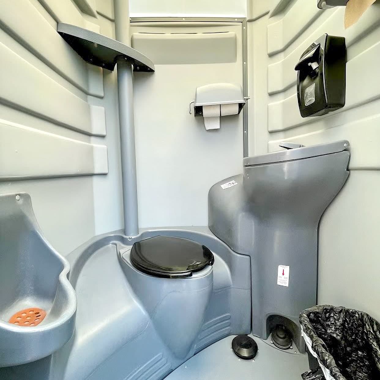 Interior of a portable restroom with toilet and urinal.