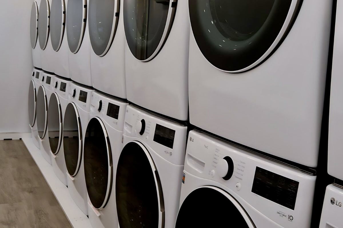 a row of modern white lg washing machines lined up in a laundromat.