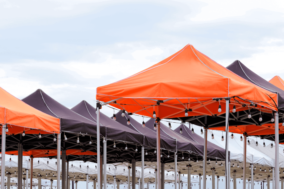 Rows of orange and grey tents and porta potties set up for an outdoor event.
