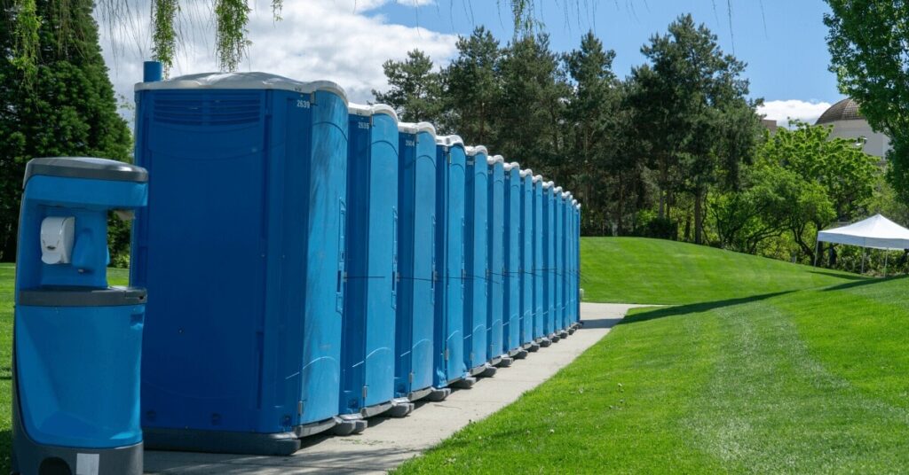 Row of Event Porta Potties lined up in a park.