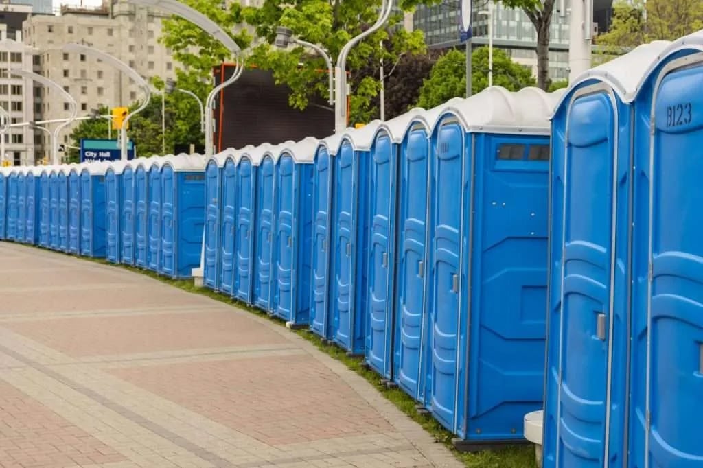 Row of blue portable toilets lined up outdoors.
