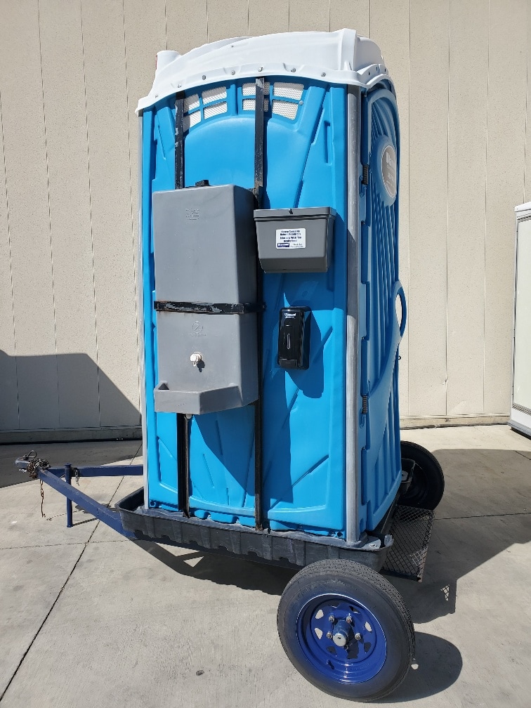 A towable porta potty on a single-axle trailer.