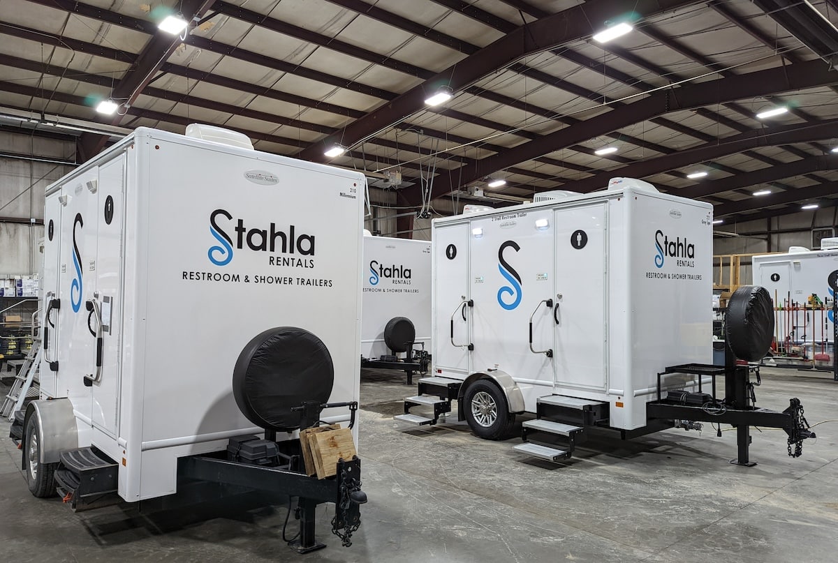 Mobile restroom and shower trailers in warehouse.
