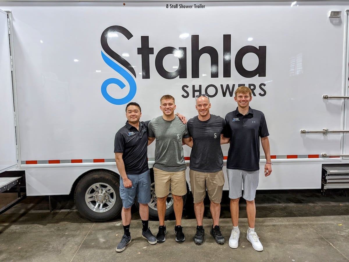 Four men standing in front of mobile shower trailer.