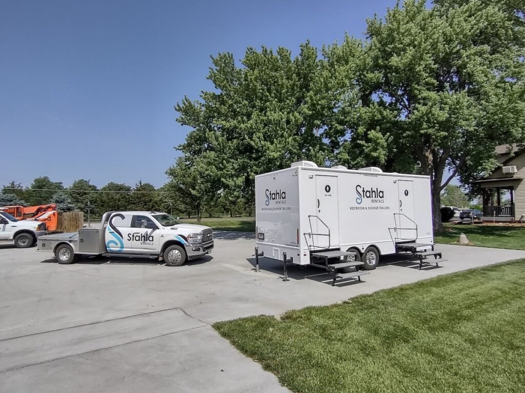 Stahla Rentals trucks with portable restroom trailers outdoors.