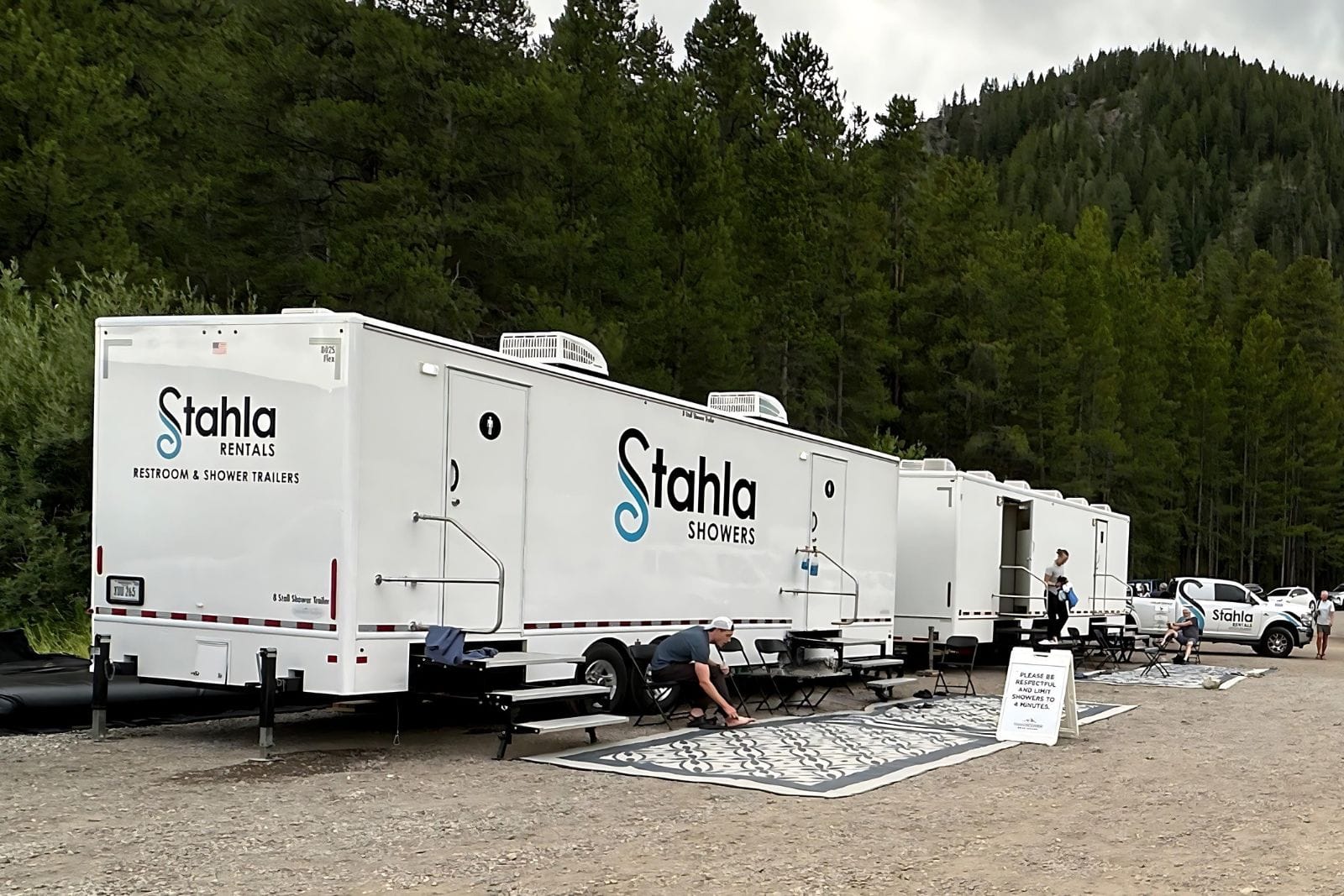 Mobile restroom and shower trailers in forest setting.