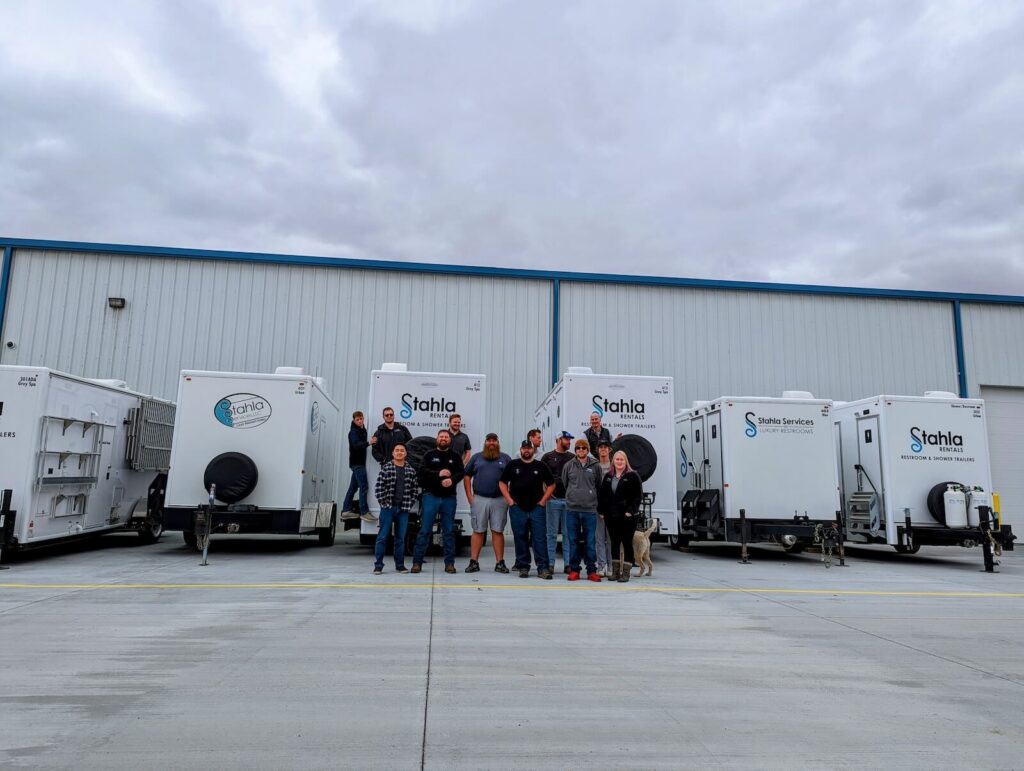 Team in front of portable restroom trailers.